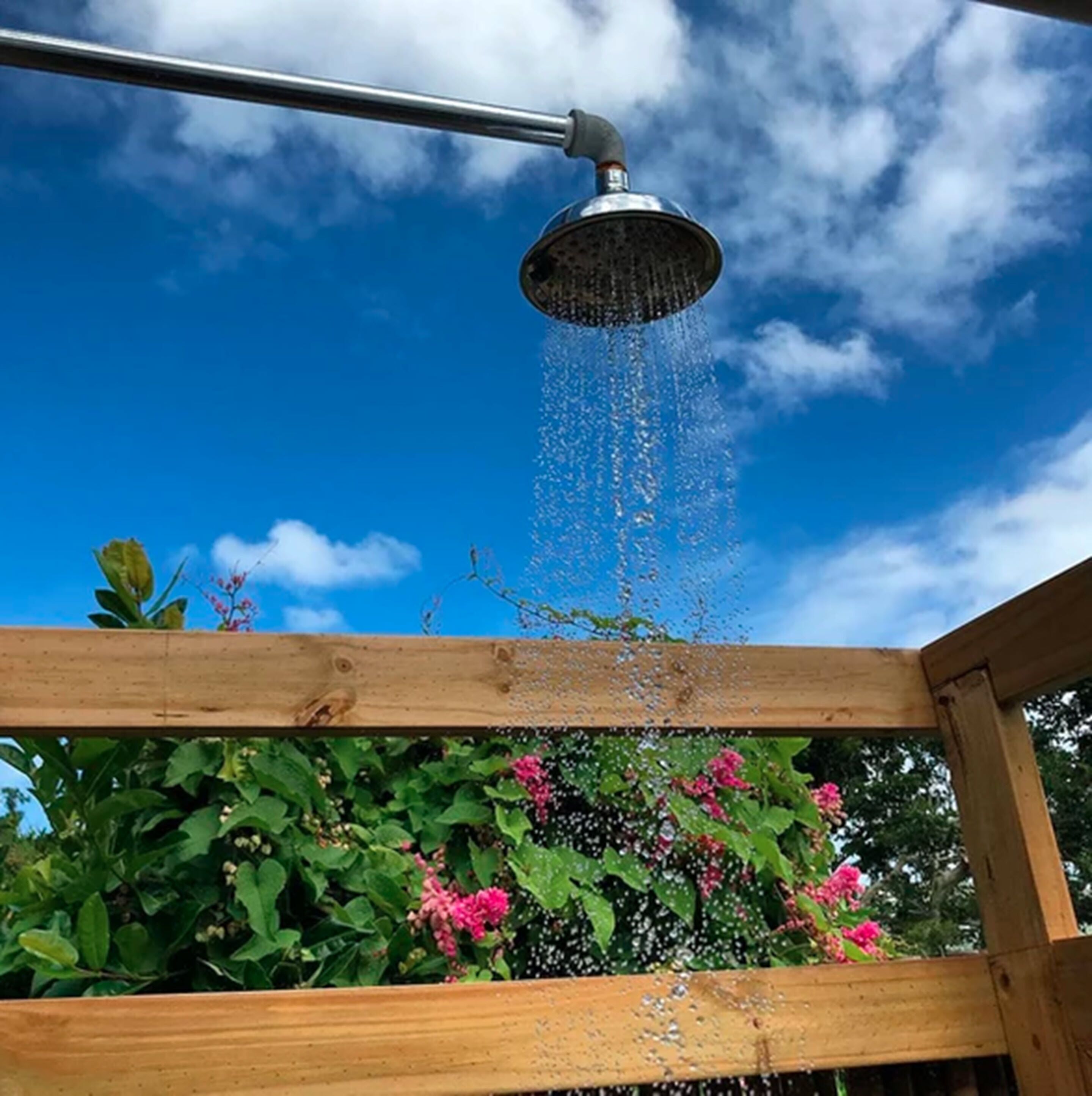 A metal showerhead with water flowing into a wooden structure.