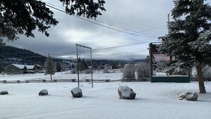 A snowy landscape with a swing set, rocks, and a building in the background. - South Fork Lodge & RV Park (South Fork)