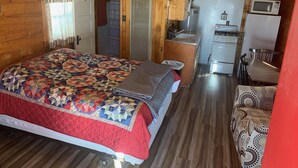 A cozy cabin with a large bed, a kitchenette, and a dining area. - South Fork Lodge & RV Park (South Fork)