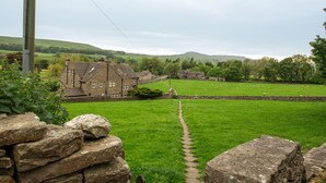 A stone wall leading to a grassy field with a stone building in the background. - Milton House Studio Apartment Suites (Leyburn)