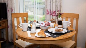 A breakfast table with a croissant, eggs, coffee, and a bowl of fruit. - Milton House Studio Apartment Suites (Leyburn)