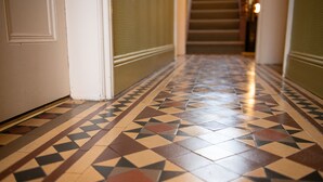 A hallway with patterned tile flooring and a staircase in the background. - Milton House Studio Apartment Suites (Leyburn)