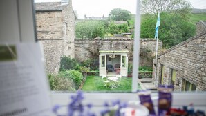 A view of a stone building with a small garden and a door leading to a room. - Milton House Studio Apartment Suites (Leyburn)
