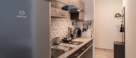 A modern kitchen with stainless steel appliances, wooden cabinets, and a tiled backsplash.