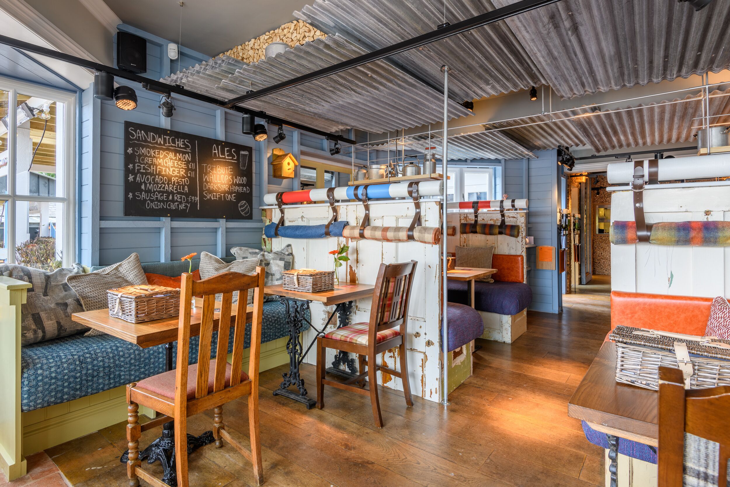 Un cafè acollidor amb interior de fusta, un menú escrit a la pissarra i diverses opcions d'aixetes, incloent una banca i cadires.
