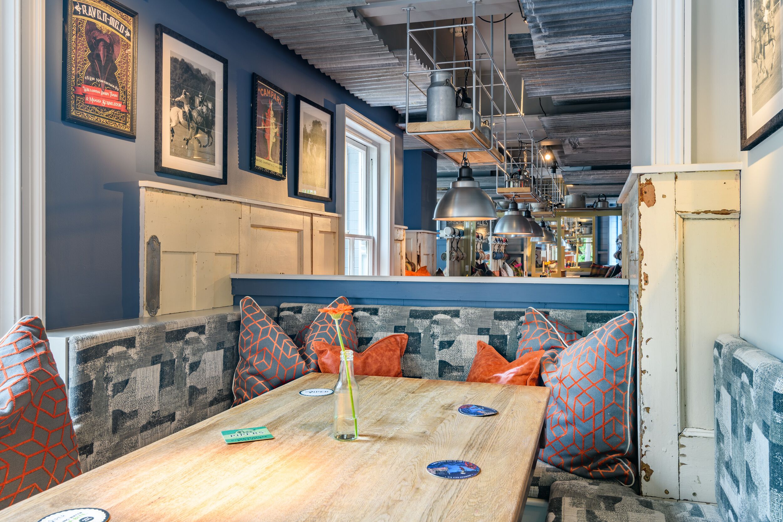 Un accogliente ristorante con tavolo in legno, cuscini decorati e manifesti d'epoca alle pareti.