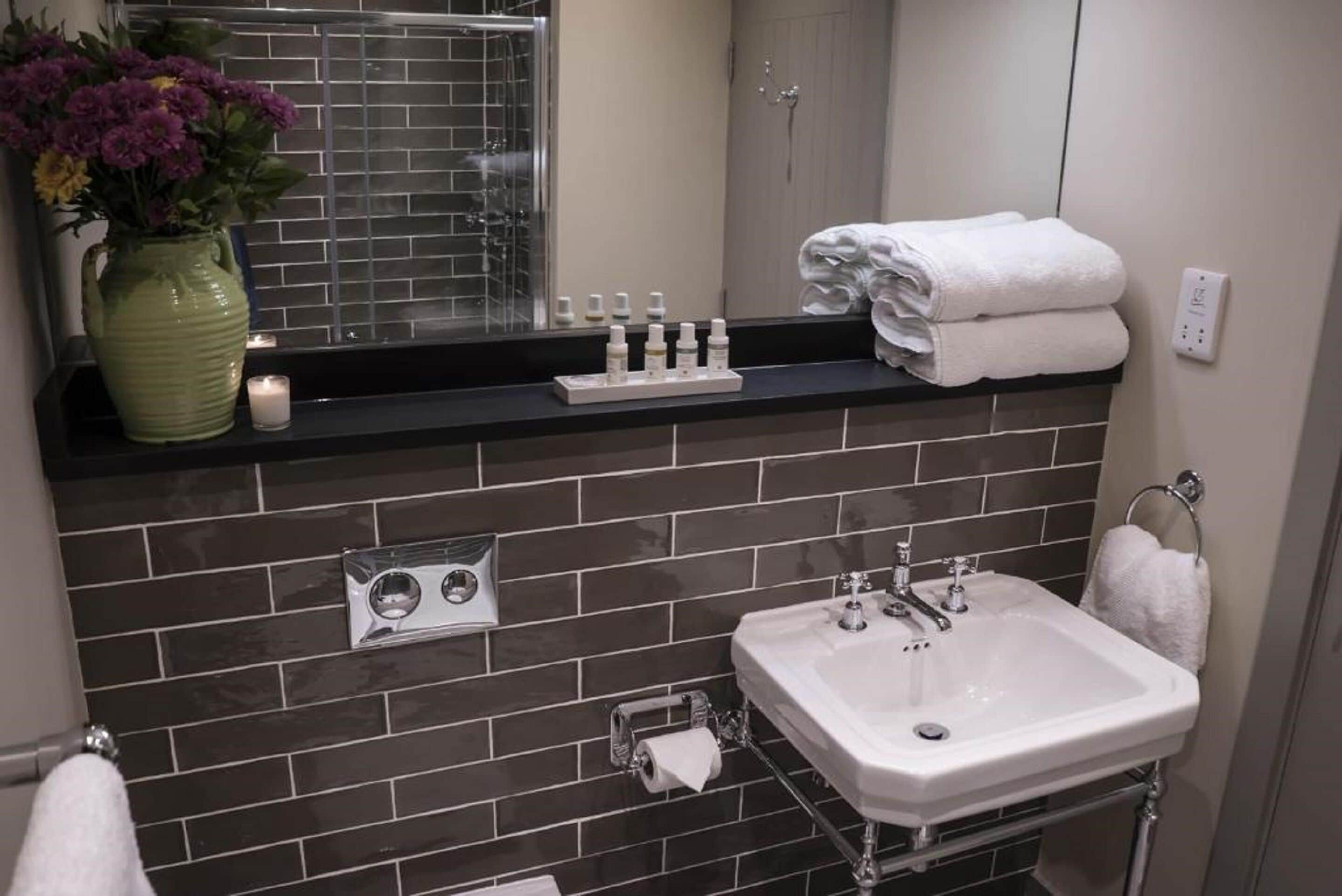 A bathroom with a sink, mirror, and toiletries on the counter.