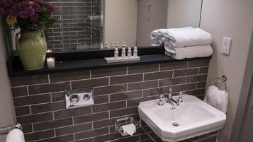 A bathroom with a sink, mirror, and toiletries on the counter.