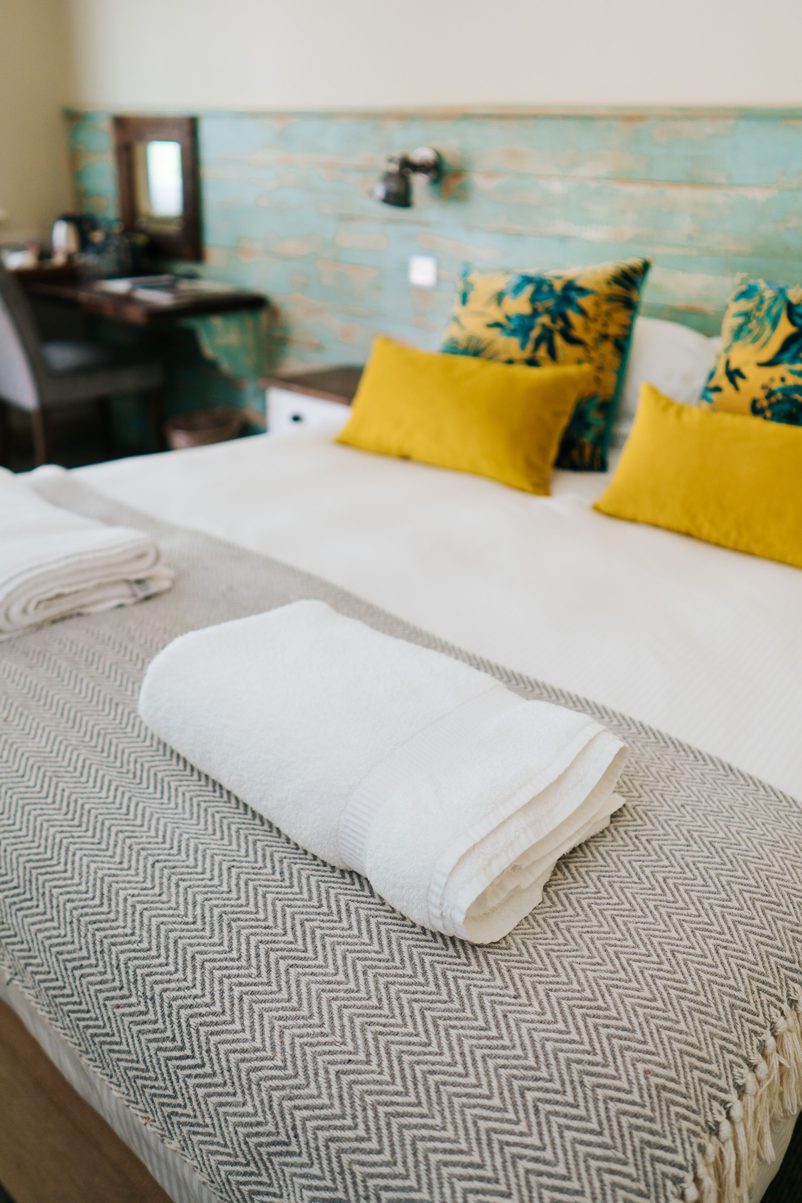 A neatly made bed with a patterned bedspread and a folded towel.