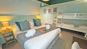 Une chambre d’hôtel avec un lit, un lit superposé, une lampe, une échelle et une petite table avec une télécommande.