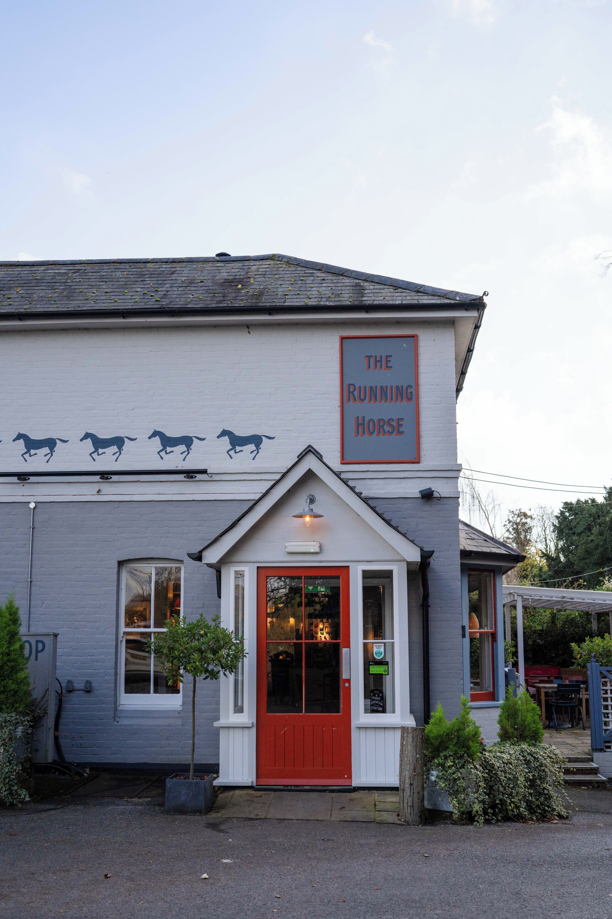 Un edificio con puerta roja y un letrero que dice "The Running Horse".