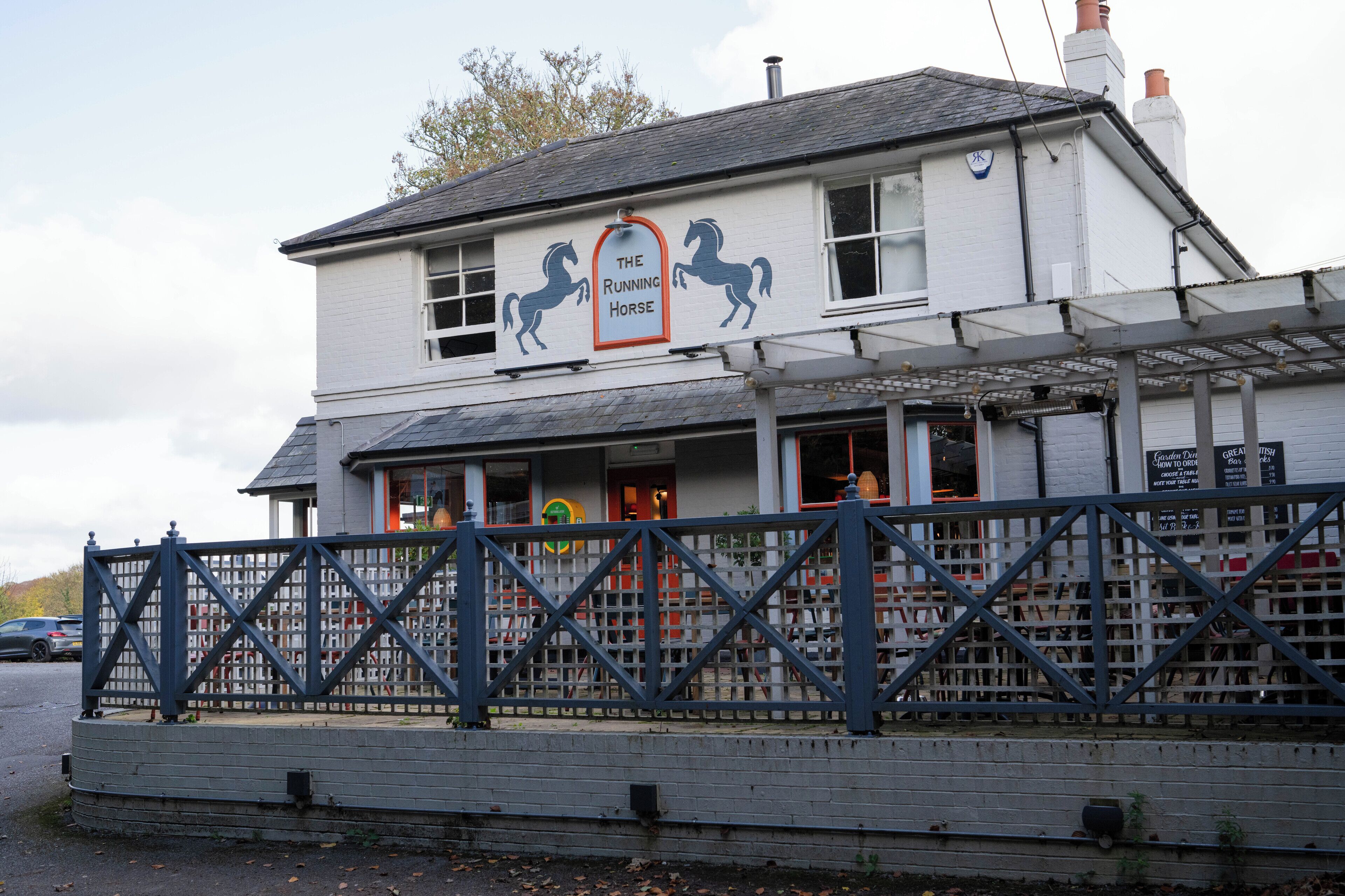 Ein zweistöckiges Gebäude mit einem Schild, auf dem 'The Running Horse' steht.