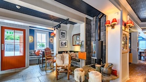 A cozy interior with a stone floor, wooden furniture, and a fireplace. - The Running Horse (Winchester)