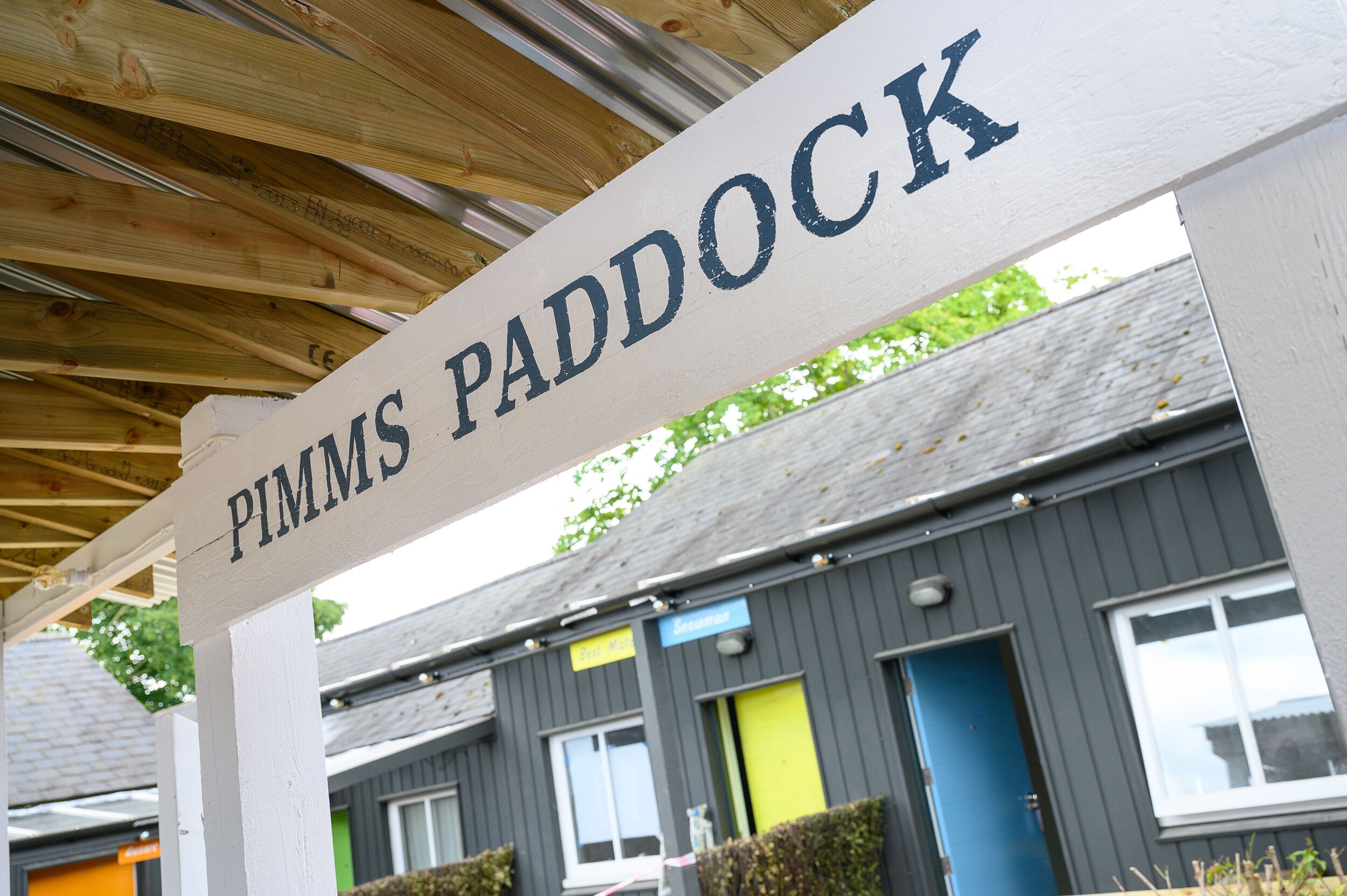 A sign for 'Pimms Paddock' with a wooden structure overhead.