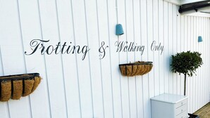 A white wall with the text "Trotting & Walking Only" and two planters with plants. - The Running Horse (Winchester)