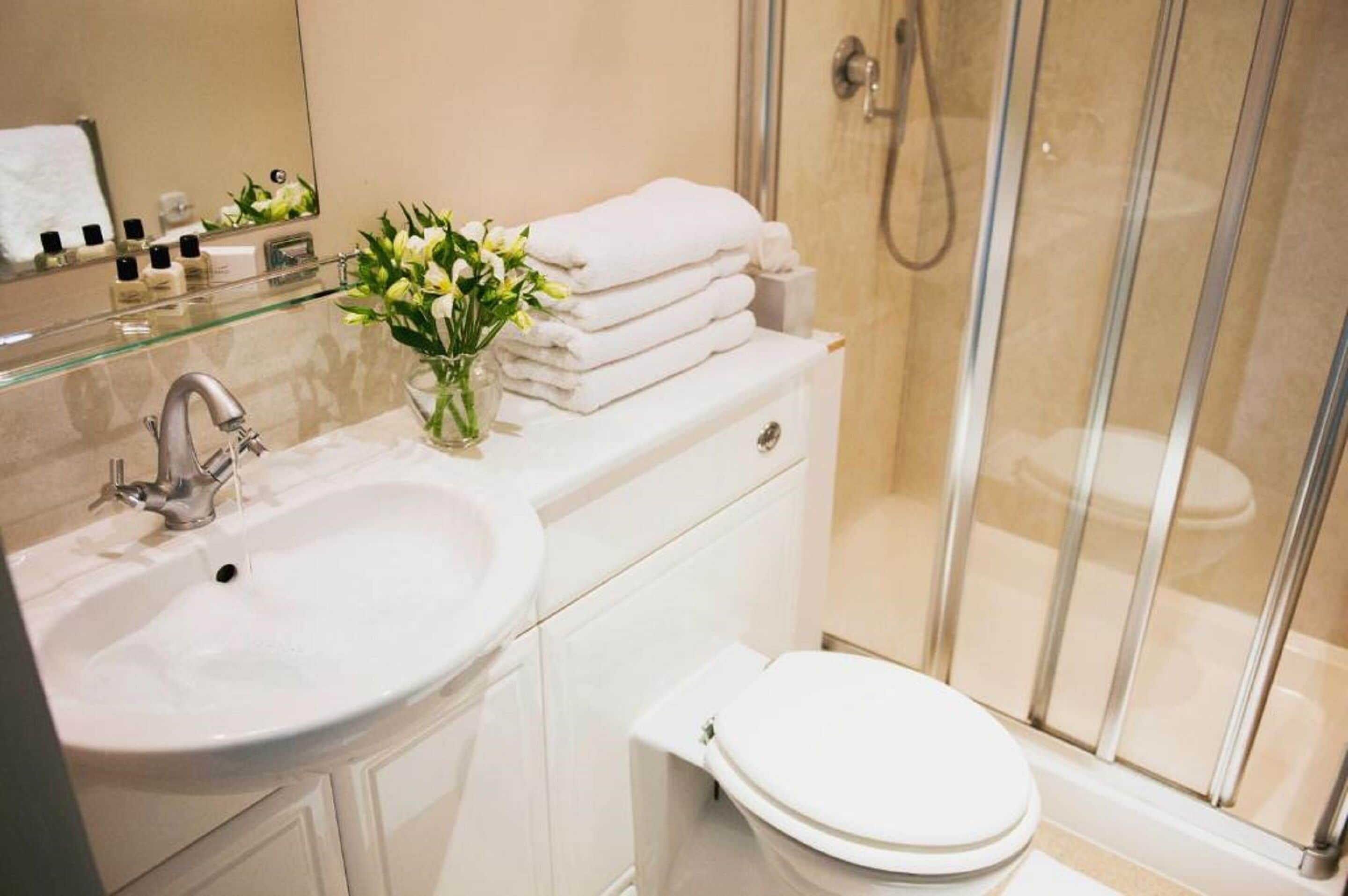 Een moderne badkamer met een douchecabine van glas, een wit wastafelmeubel en een toilet.