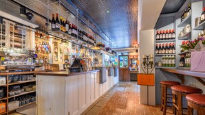 A bar area with shelves of bottles, a coffee machine, and stools. - The Running Horse (Winchester)