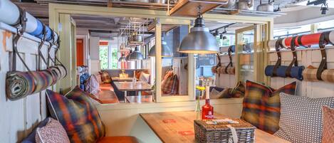 A cozy seating area with a wooden table, benches, and a variety of pillows.