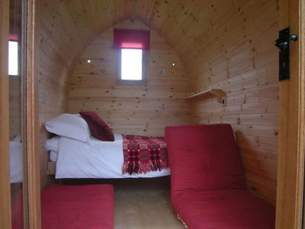 A cozy room with a bed, a red couch, and a small window.