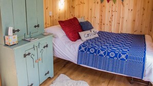 A wooden room with a bed, a light blue cabinet, and a window with a heart-shaped decoration. - Siabod Huts (Llanrwst)