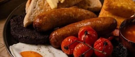 Ένα πιάτο για πρωινό με αυγά, λουκάνικα, ντομάτες και ψωμί.