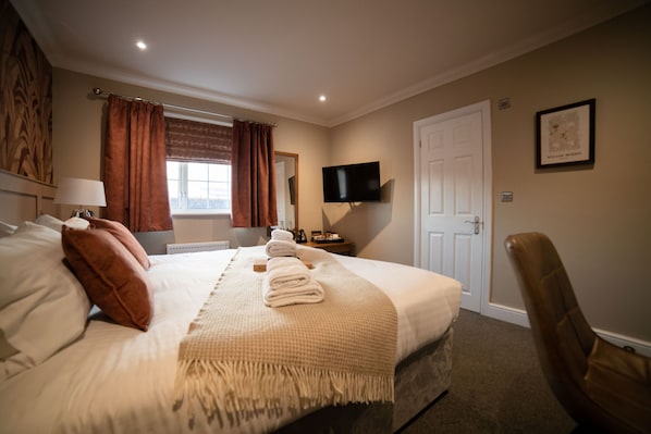 A neatly made bed with pillows and a blanket, a flat-screen TV mounted on the wall, a door, and a framed picture on the wall. - Harper's Steakhouse with Rooms, Southampton Swanwick Marina (Southampton)