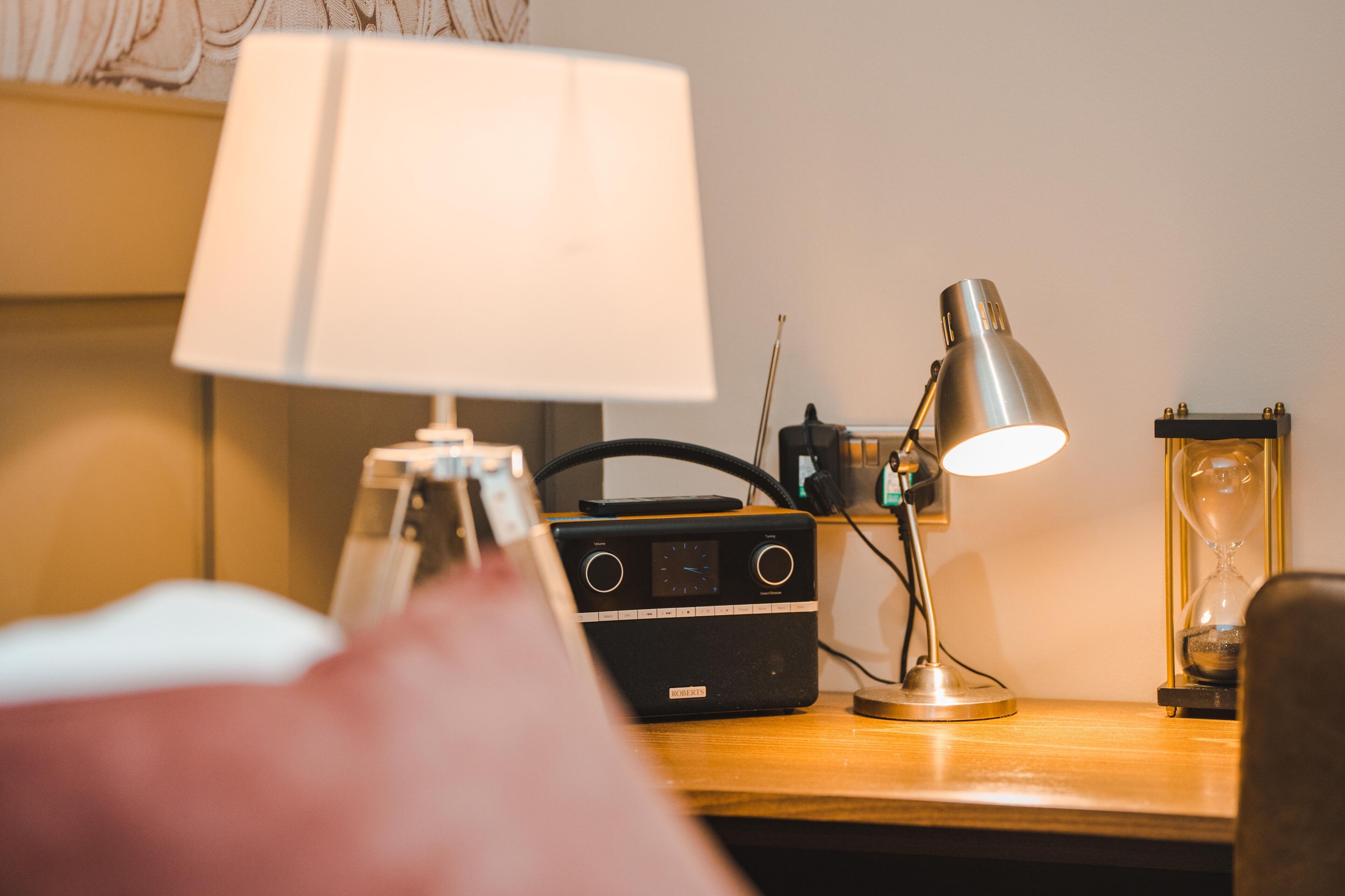 Una scrivania di legno con una radio, una lampada e una clessidra.