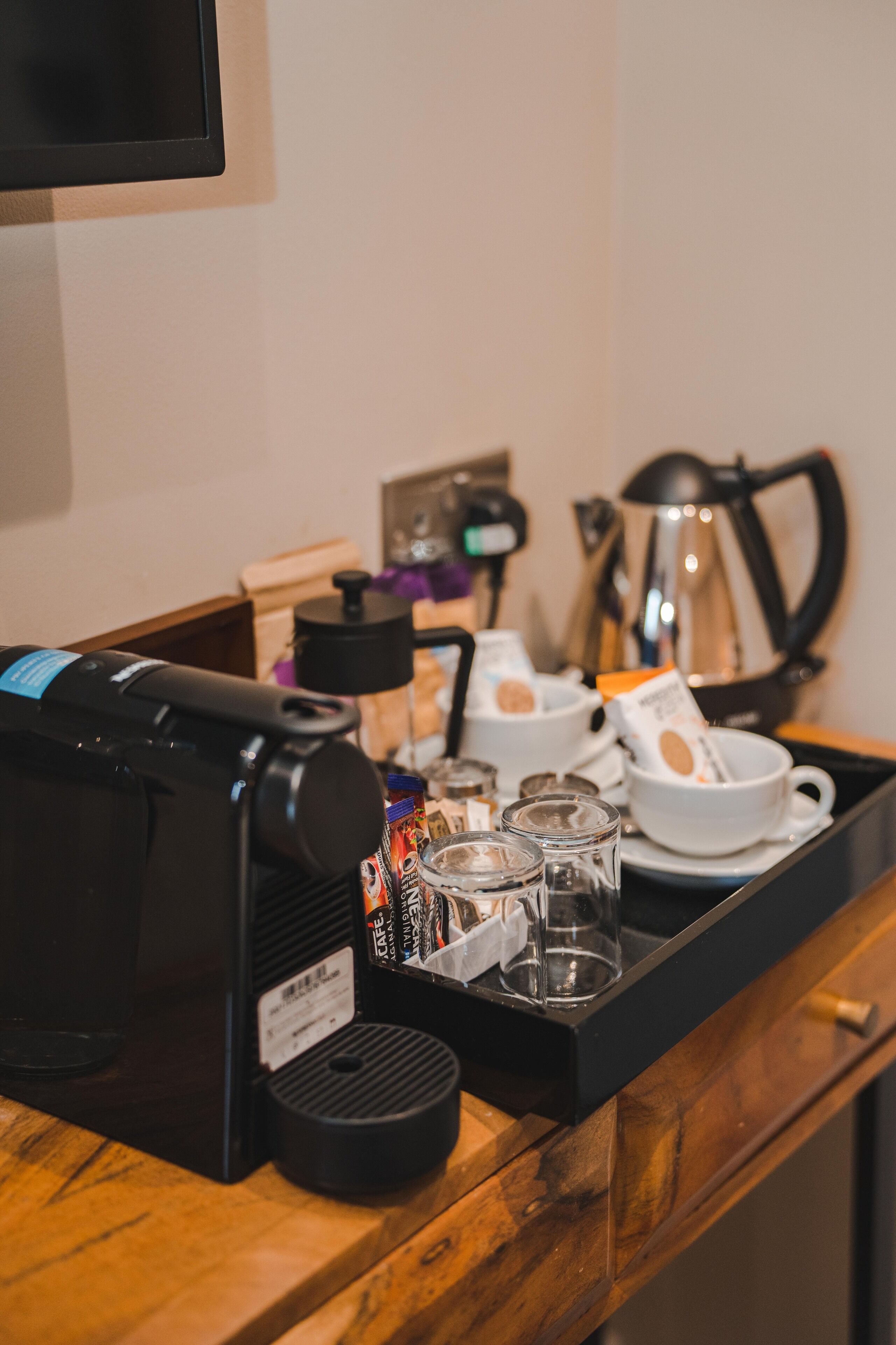 A coffee station with a coffee machine, cups, and a tray.