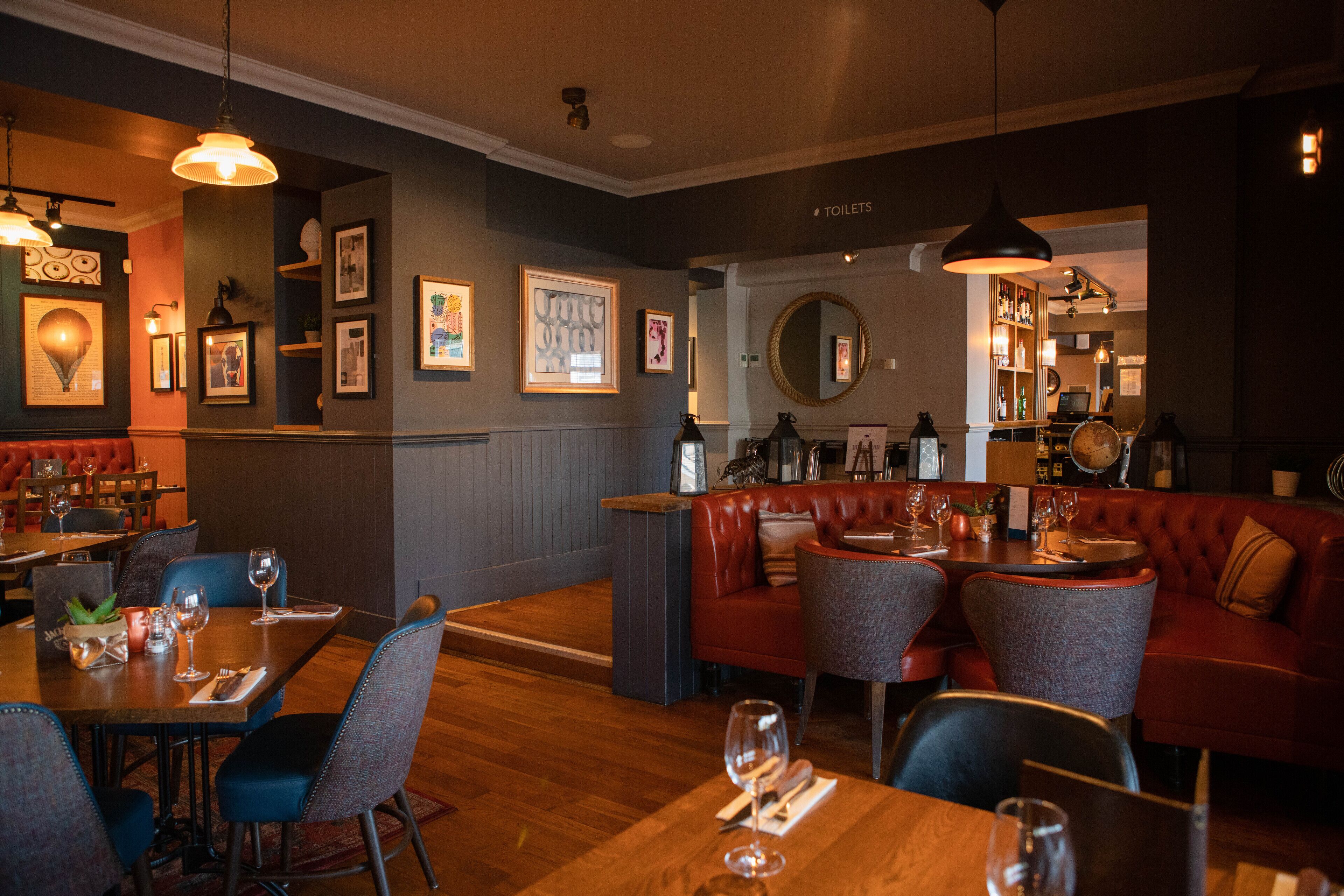 Un restaurant doté d’un plancher en bois, de banquettes en cuir rouge et de tableaux encadrés qui ornent les murs.