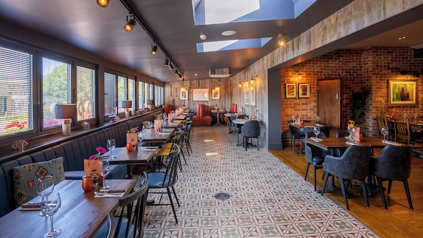 Un restaurant avec un long comptoir, des banquettes et un mur en briques.