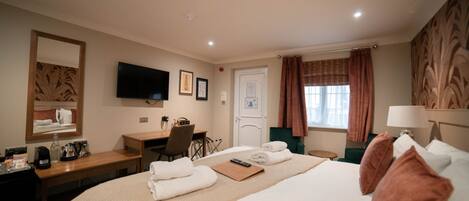 A hotel room with a bed, a desk, a chair, a television, and a window with curtains.