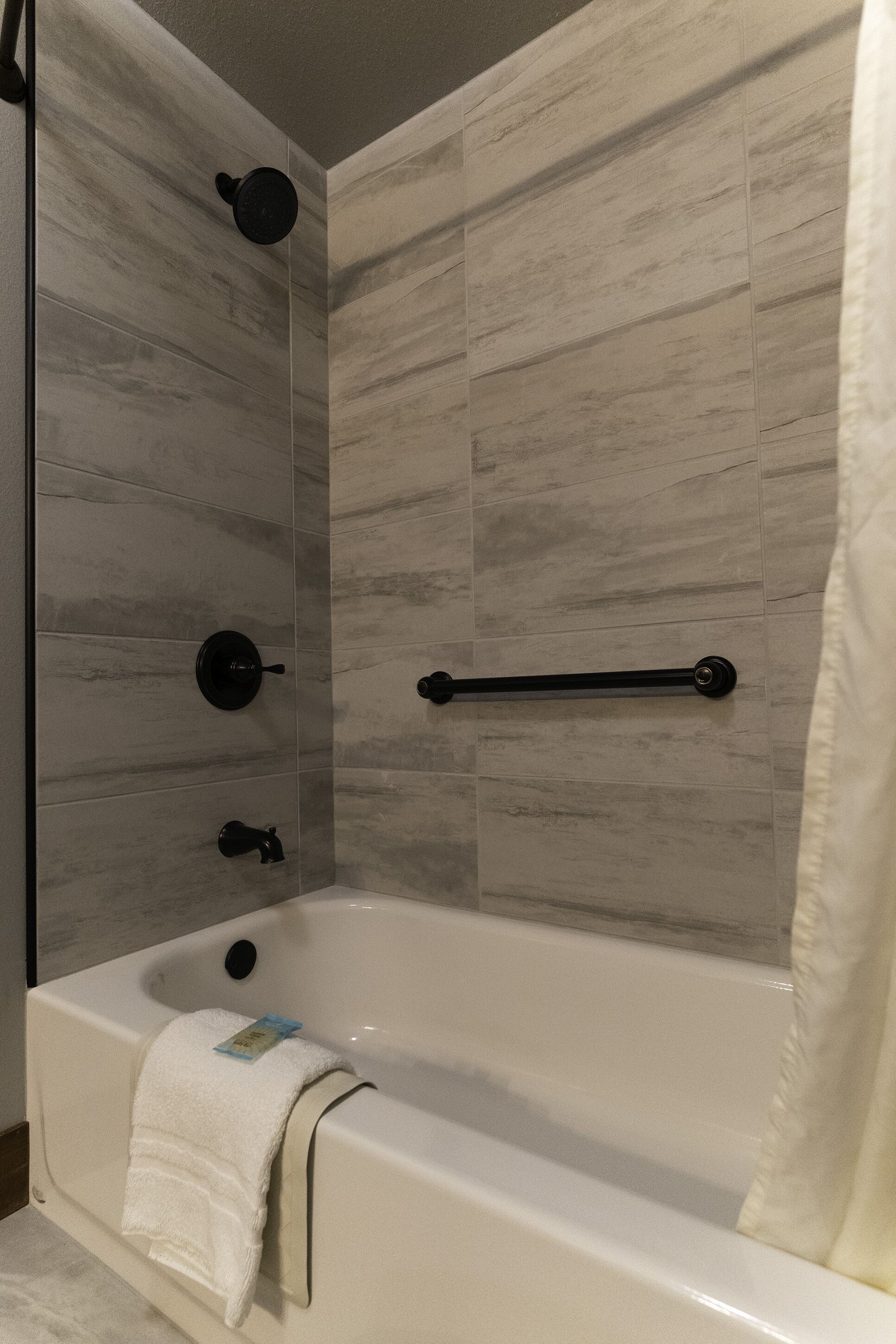 A modern bathroom with a bathtub, a towel rack, and a shower head.