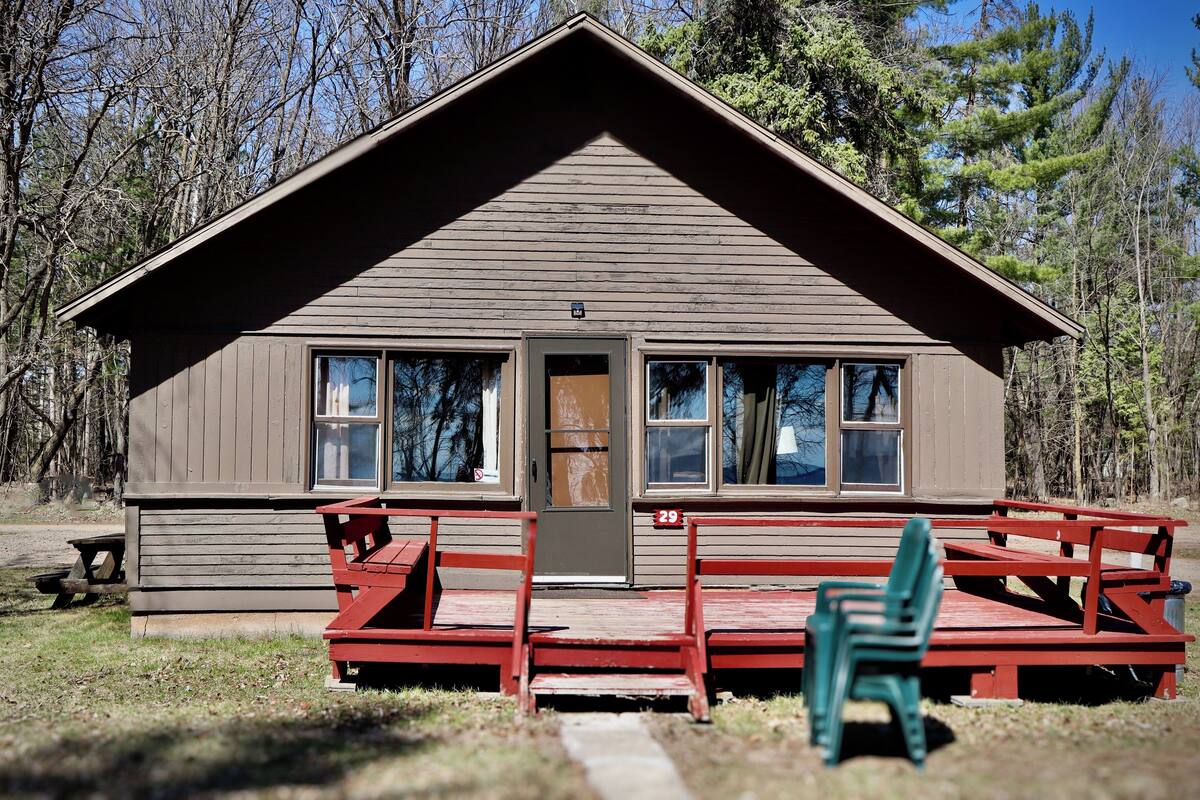 Een chalet met een veranda, een deur en een bord met het nummer 29.