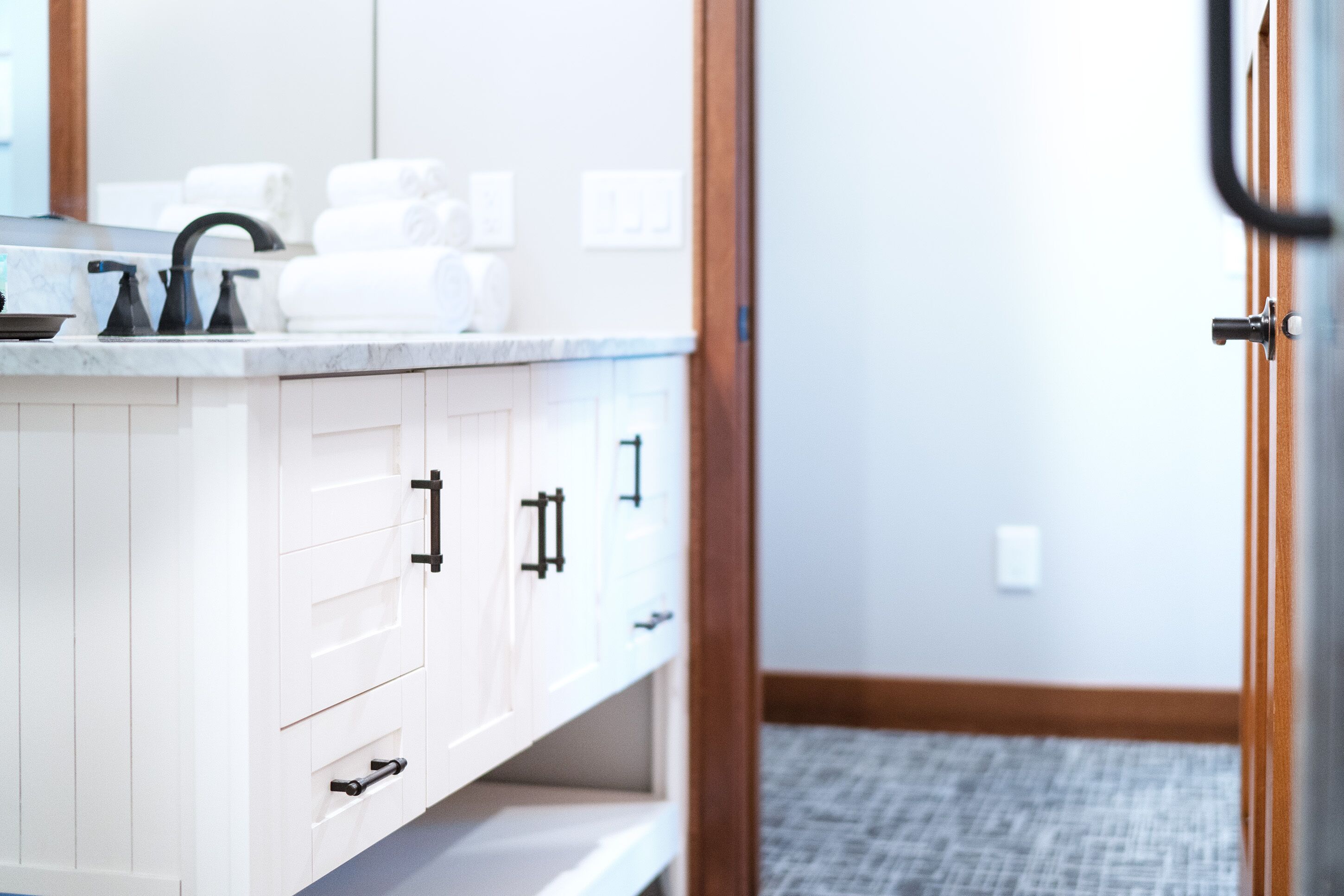 A modern bathroom with a white vanity, black faucets, and a mirror above the sink.