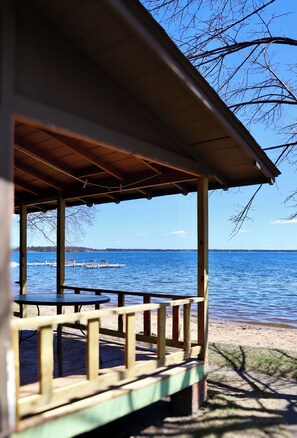 A wooden deck with a table and chairs overlooking a calm lake.
