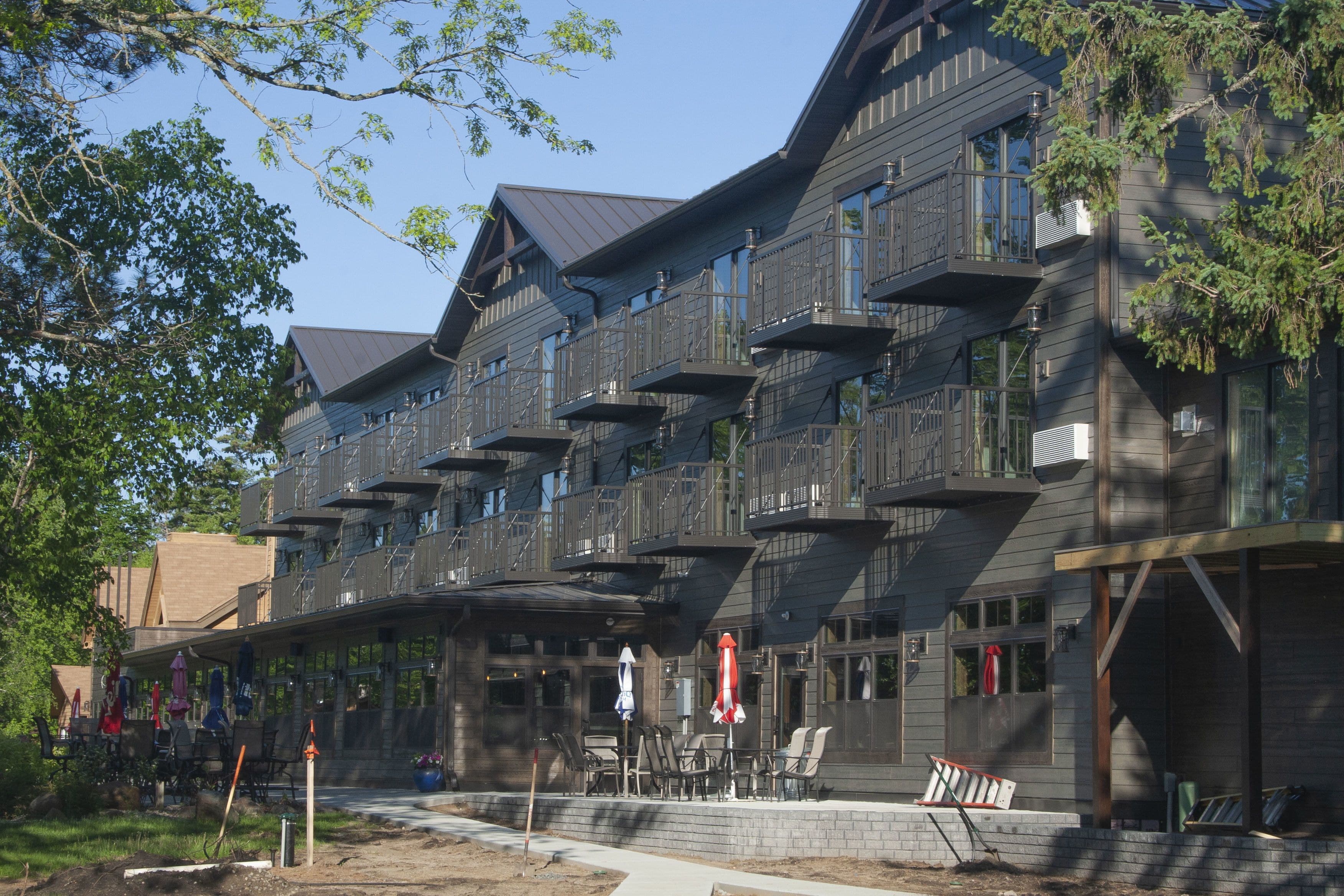 A multi-story building with balconies, outdoor seating, and a brick facade.