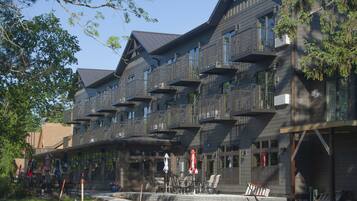 A multi-story building with balconies, outdoor seating, and a brick facade.