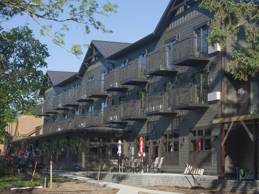 A multi-story building with balconies, outdoor seating, and a brick facade.