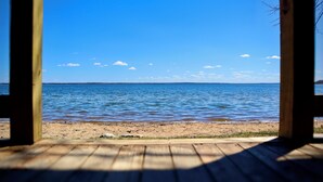 A wooden deck leading to a beach with a view of the sea and a clear sky. - Ruttger's Birchmont Lodge (Bemidji)