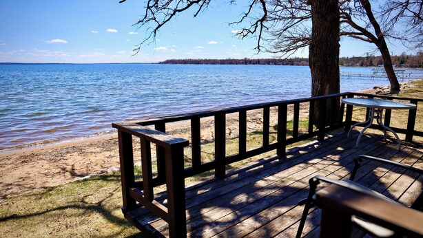 A wooden deck with a table and bench overlooking a lake. - Ruttger's Birchmont Lodge (Bemidji)