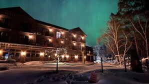 A snow-covered building with multiple windows and a tree in the foreground. - Ruttger's Birchmont Lodge (Bemidji)