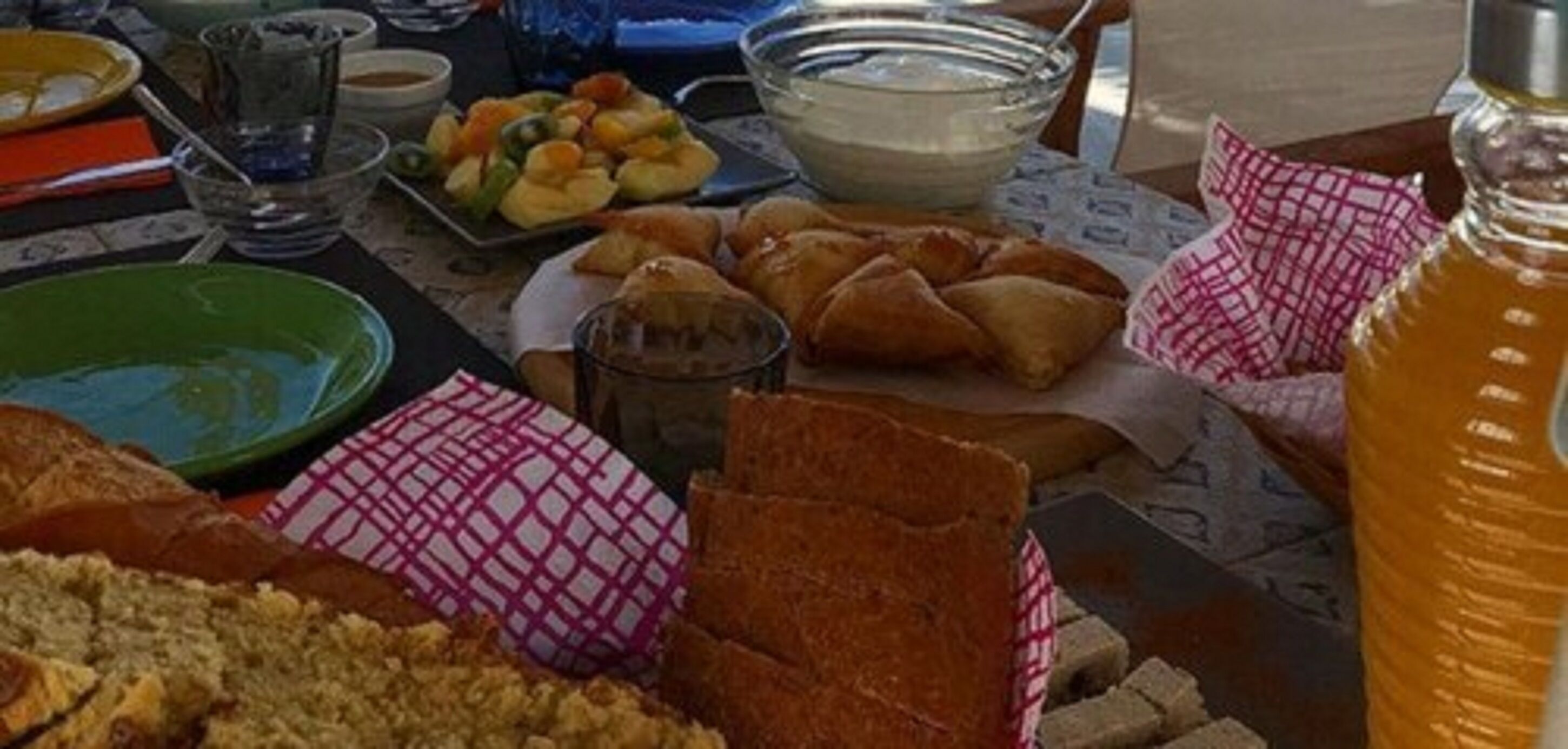 Una mesa con diferentes alimentos, incluyendo pasteles, un tazón de sopa y una botella de miel.