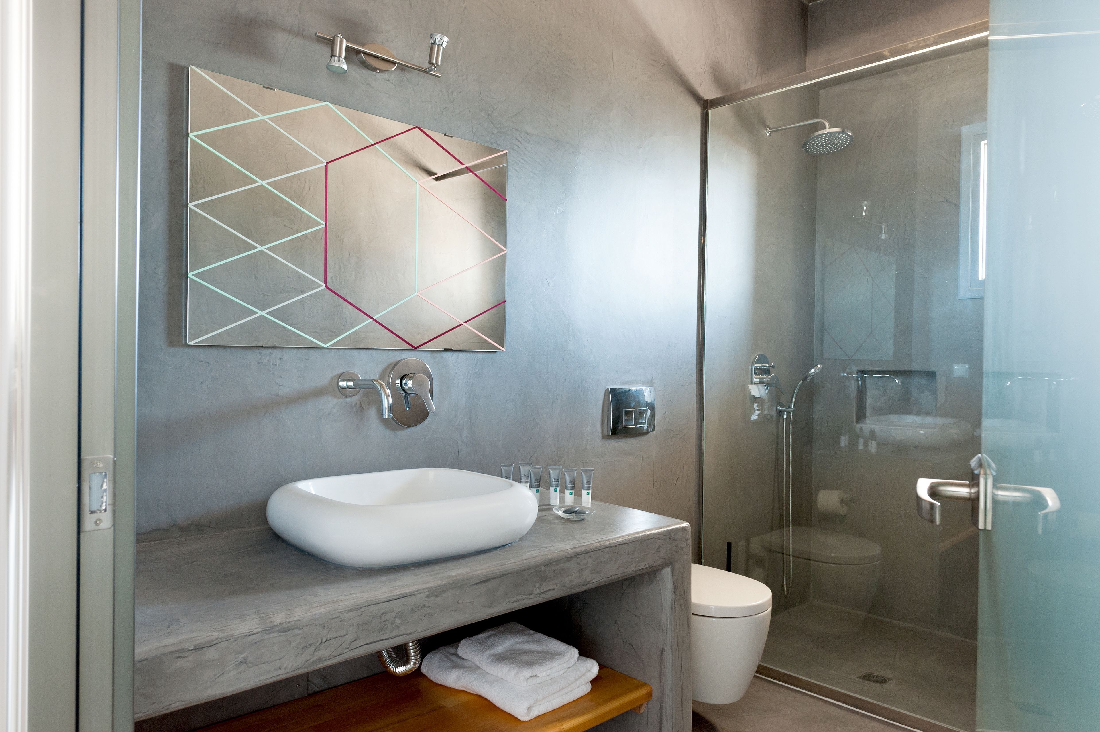 A modern bathroom with a large mirror, a white sink, and a glass-enclosed shower.