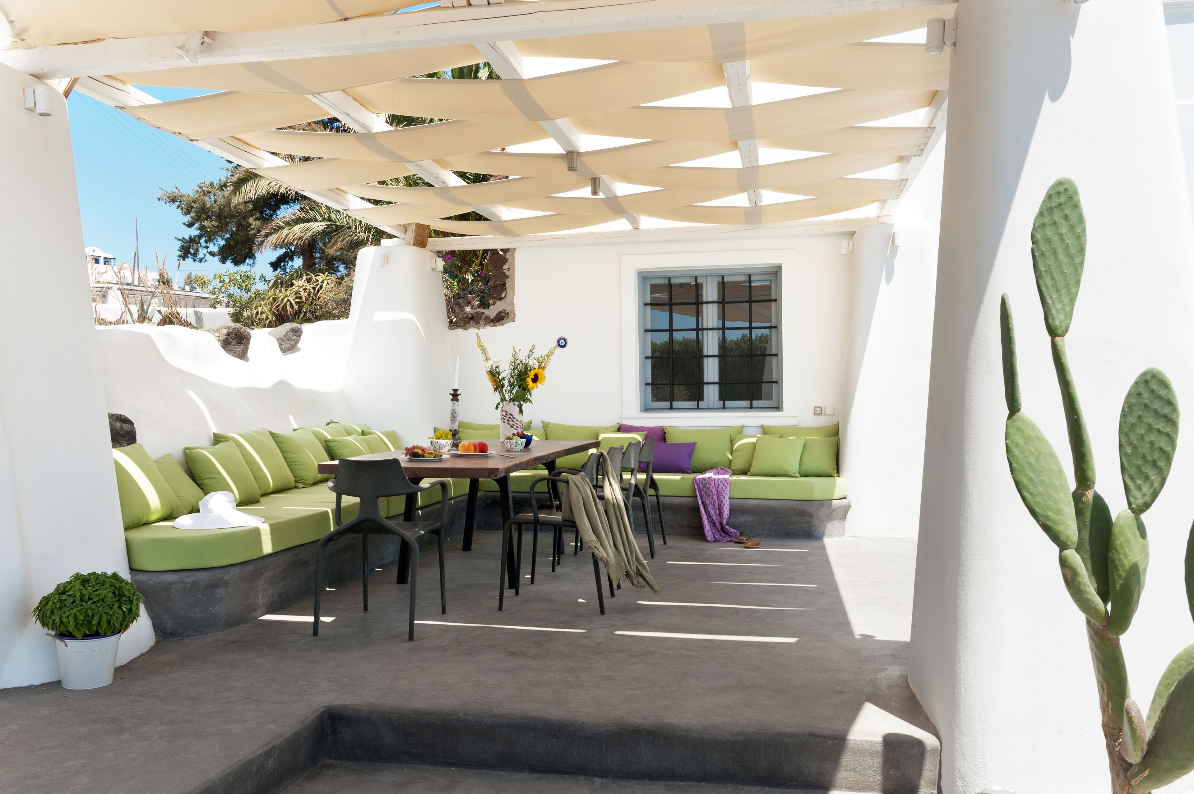 An outdoor patio with a dining table, chairs, and a green sofa.