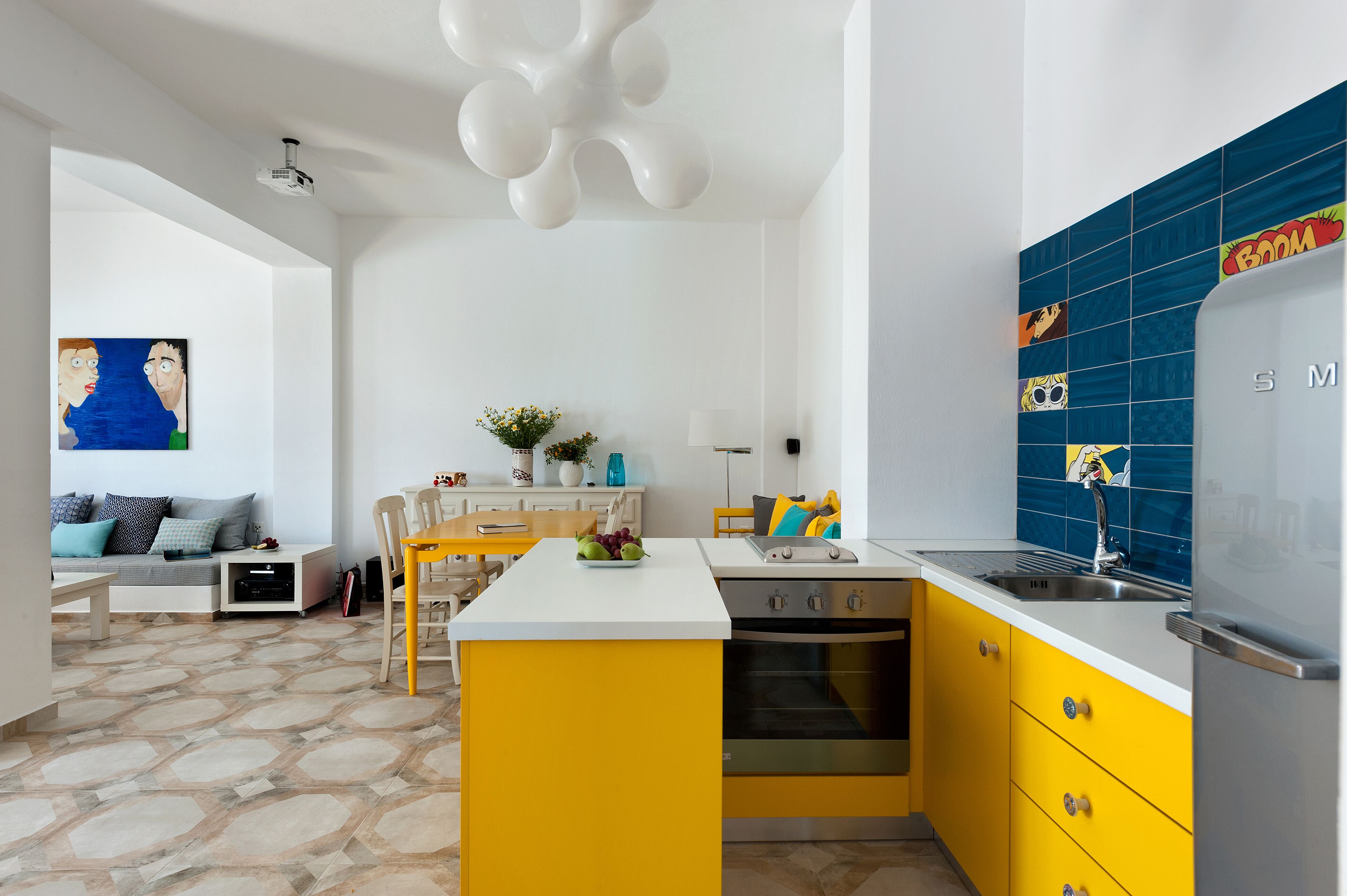 A modern kitchen with yellow cabinets, a white countertop, and a blue backsplash.