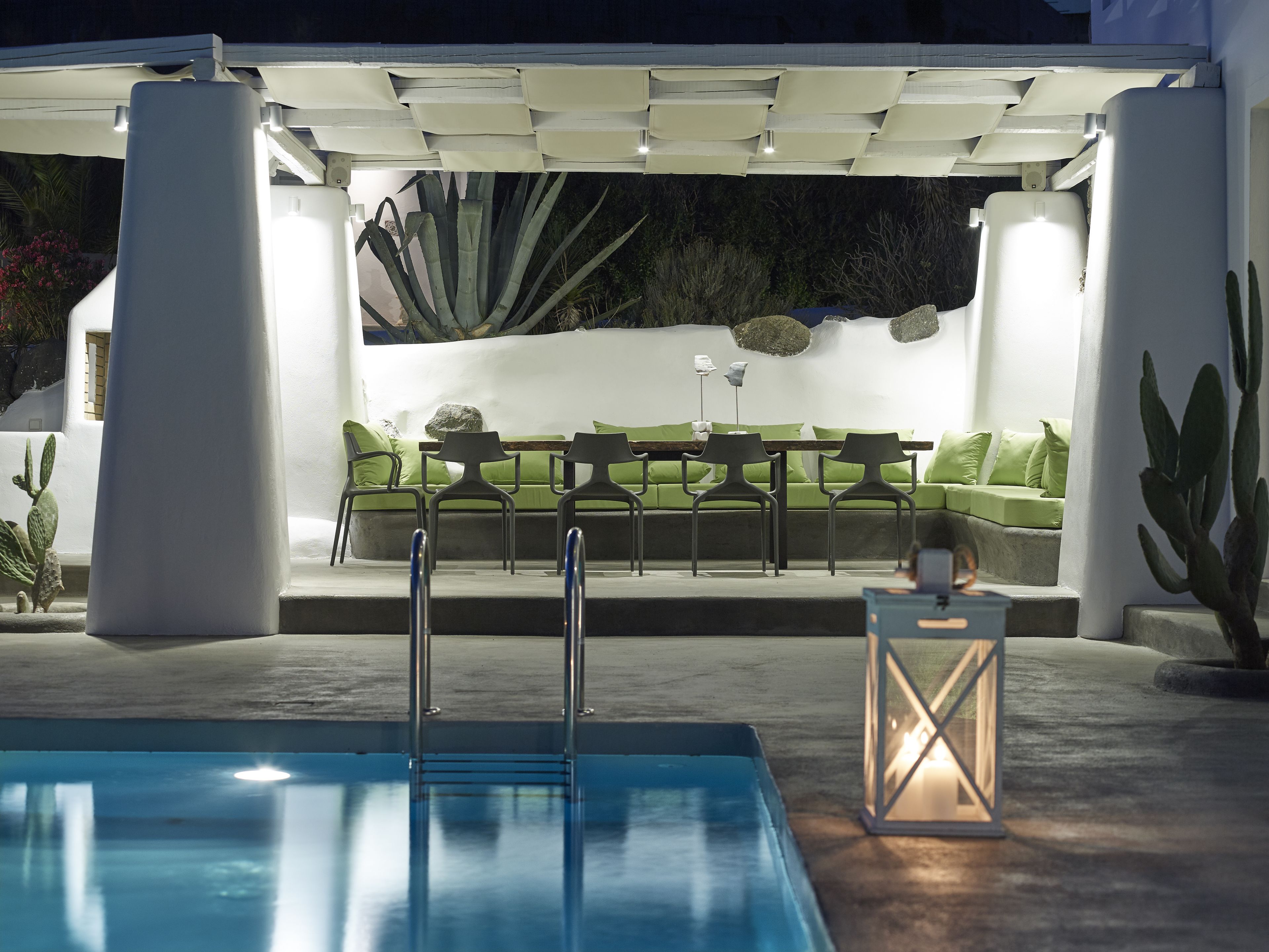 A pool area with a seating area, chairs, and a lantern.