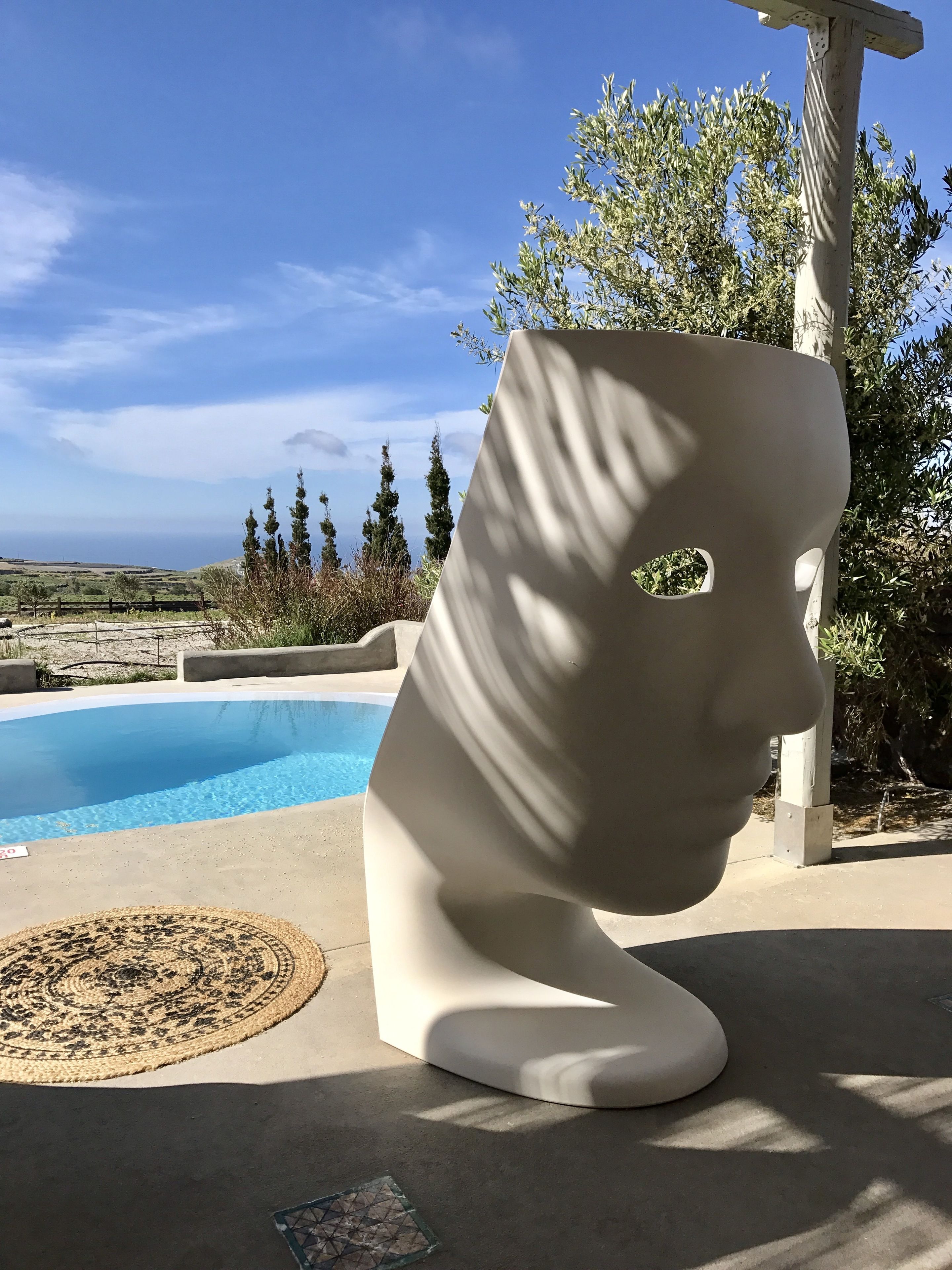 A modern sculpture near a pool with a clear view of the landscape.