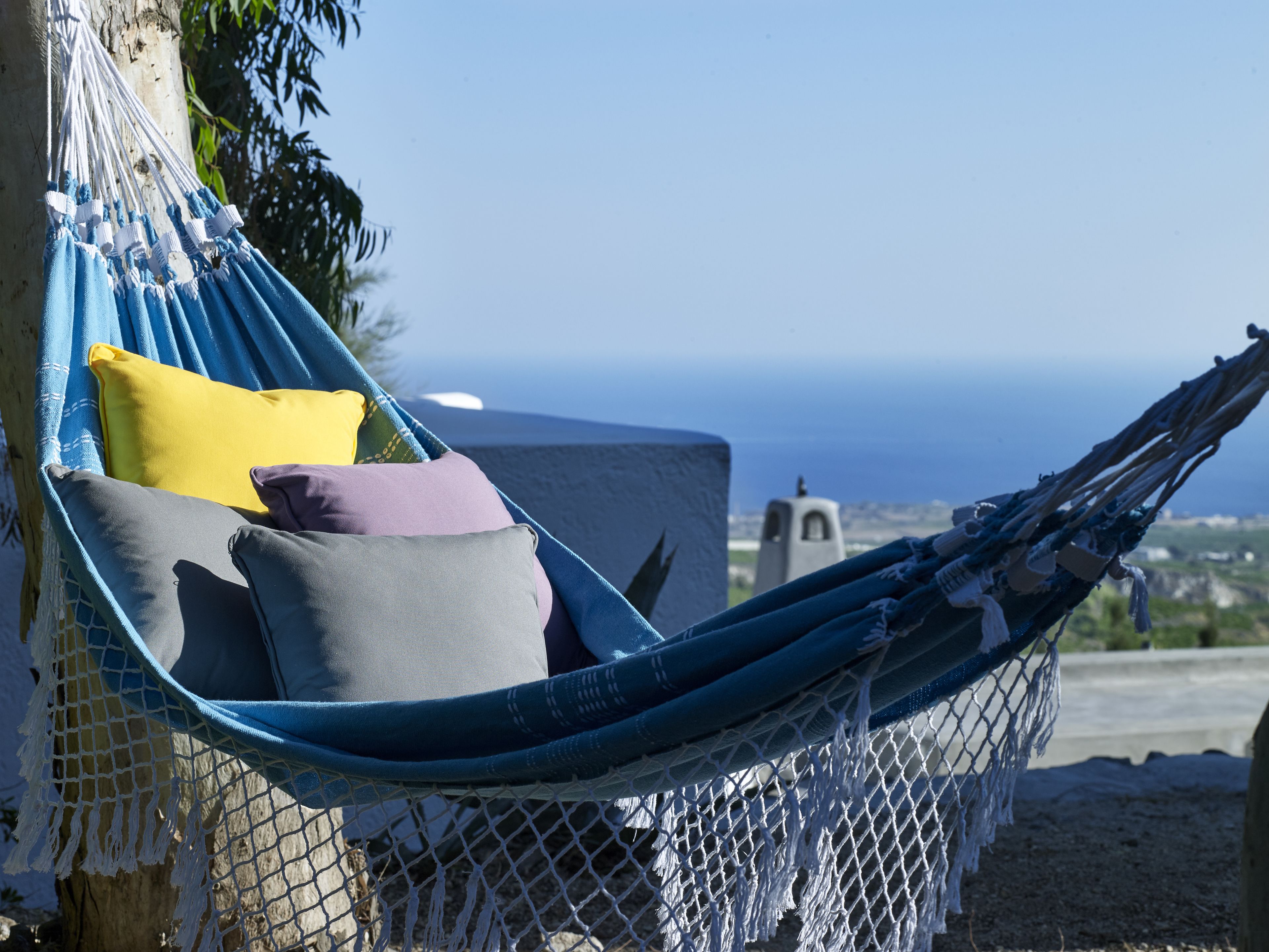 A hammock with pillows, set against a backdrop of a clear sky and distant landscape.
