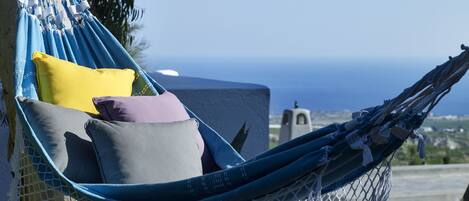 A hammock with pillows, set against a backdrop of a clear sky and distant landscape.