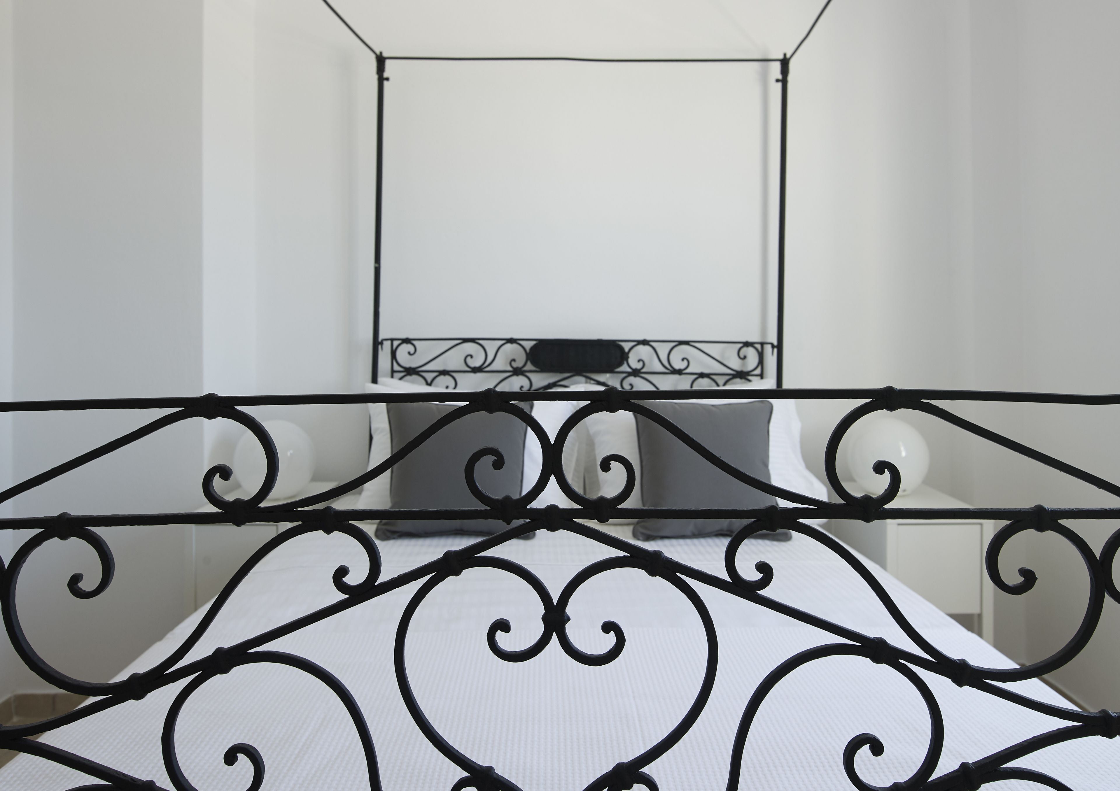 A bed with a white mattress and black metal headboard.